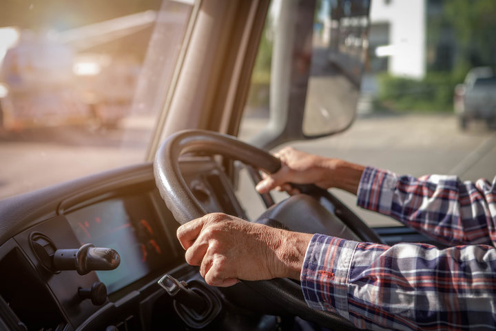 Experienced truck driver's hands on the steering wheel representing years of safe driving