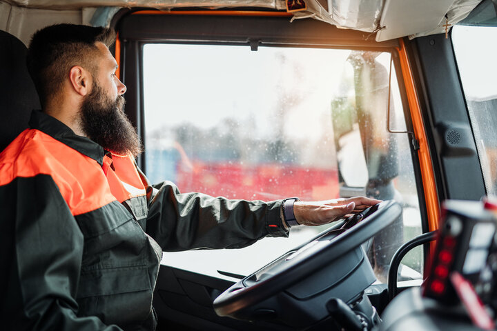 Professional truck driver smiling while wearing a high-visibility safety vest