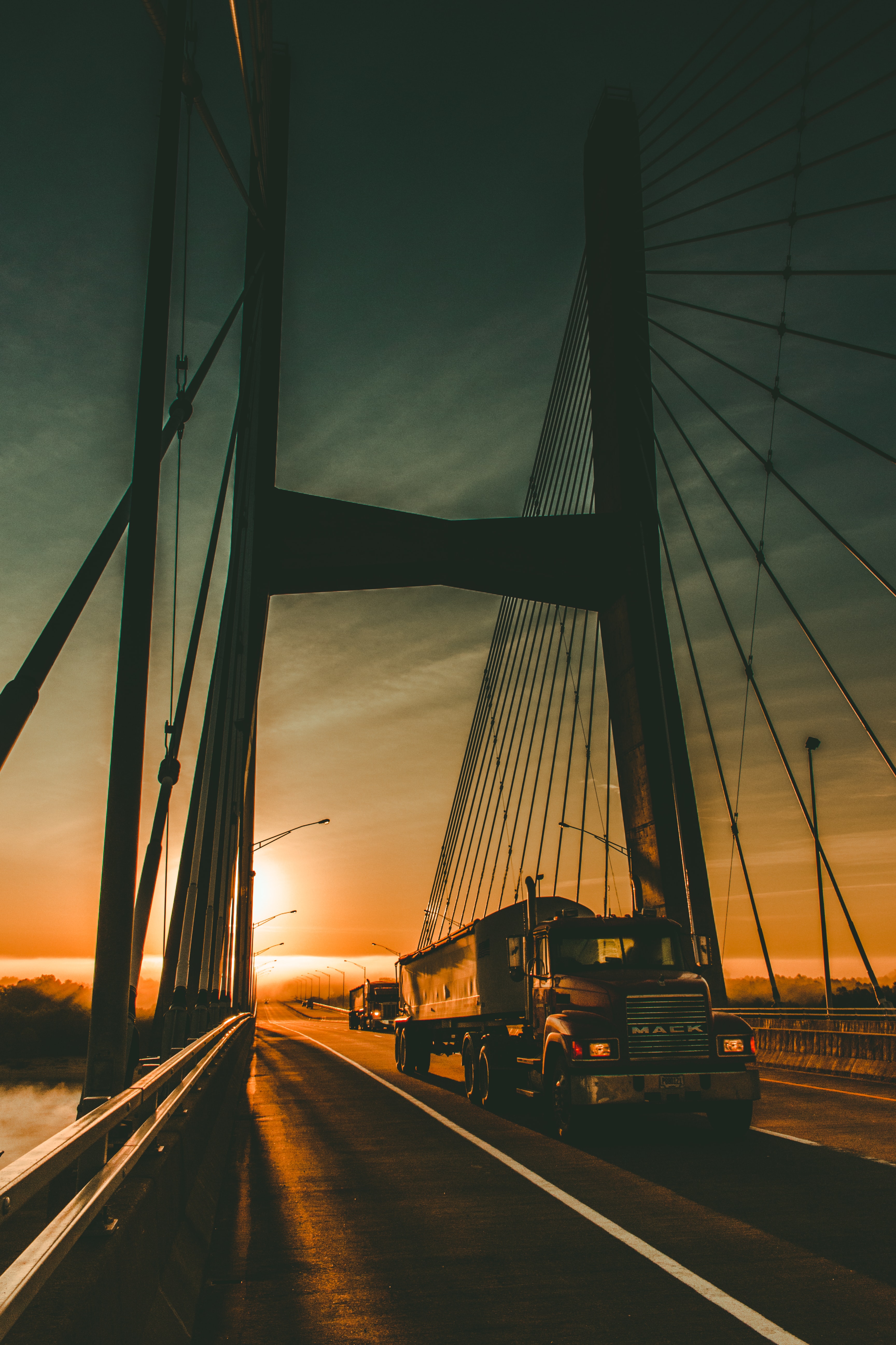 Semi truck crossing a suspension bridge at sunset
