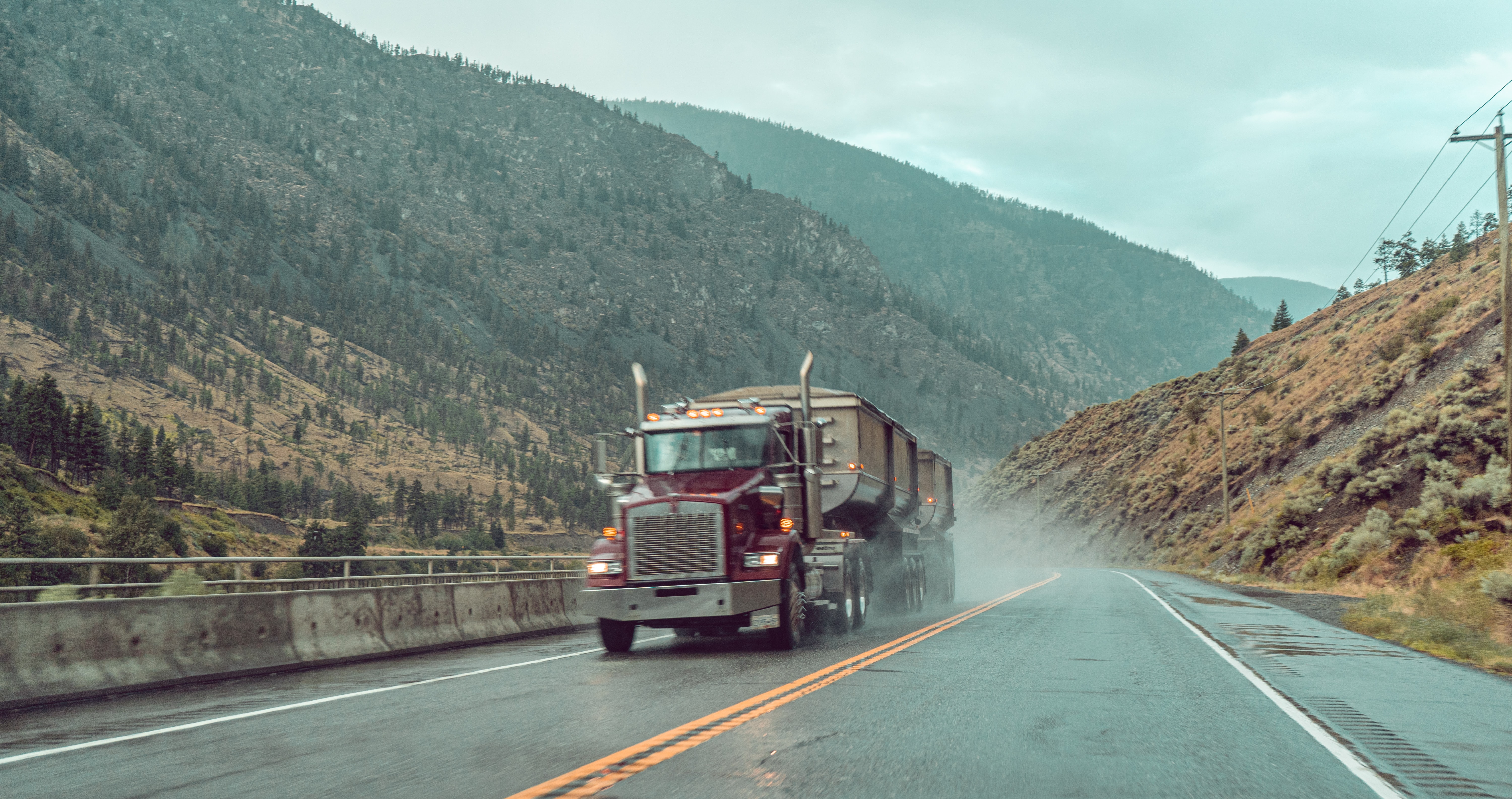 Commercial truck navigating a rainy mountain road demonstrating weather mastery